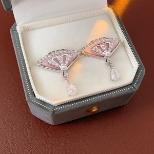 Detailed view of silver fan-shaped earrings with pink zircon and pearls in a velvet box