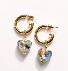 Close-up of heart-shaped Murano style glass charms on golden metal hoop earrings