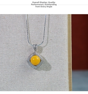 Detail shot of a square silver pendant with yellow gemstone on a jewelry display board