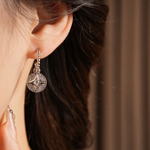 Dettaglio di orecchini a C in argento con stelle in zircone indossati da una modella