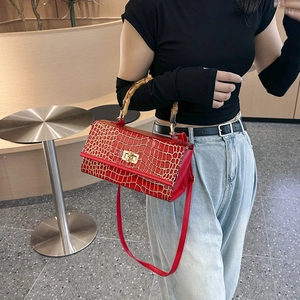 Detail of red crocodile pattern handbag with classic bamboo handle and metal lock