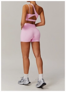 Détail du haut de sport rose à épaule unique avec découpe au dos et short de yoga
