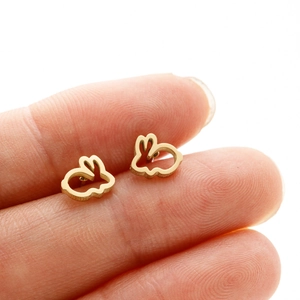 Minimalist gold hollow-out rabbit stud earrings shown on finger for size comparison