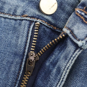 Gros plan sur le denim délavé bleu avec fermeture éclair dorée et bouton métallique