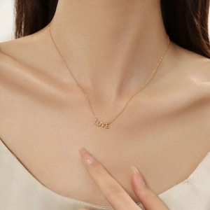 Dettaglio della collana dorata con ciondolo LOVE e catena sottile minimalista