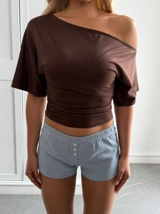 Detail of a brown one-shoulder Y2K cropped top with pleated belly design and striped shorts
