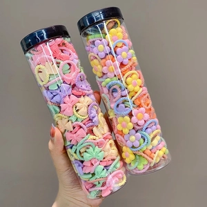Detailed view of colorful kids hair ties with floral and bow charms in clear storage tubs