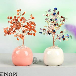 Natural crystal money trees with orange and colorful stones in ceramic pots on a book