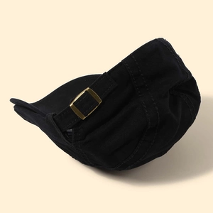 Detail shot of the vintage bronze adjustable metal buckle on a black cotton beret cap