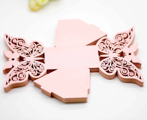 Flat lay of pink laser-cut butterfly wedding favor boxes with pearlescent paper finish