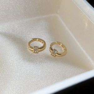 Close-up of 18k gold plated hoop earrings with zircon stones on beige fabric