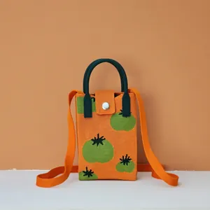 Detail of orange knitted mini phone bag with green fruit pattern and metal snap button