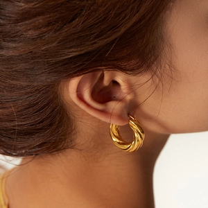 Fashionable gold twisted hoop earrings for women with polished stainless steel texture