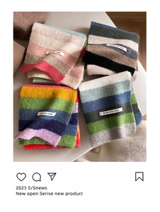 Close-up of colorful striped mohair scarves folded in pink, grey, and rainbow patterns
