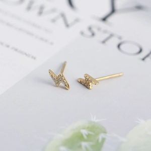 Detail of lightning bolt stud earrings in gold finish with sparkling zircon stones