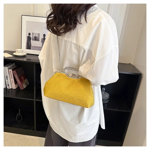 Dettaglio borsa a conchiglia in strass giallo con catena indossata su camicia bianca