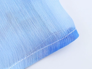 Dettaglio macro della texture in chiffon sfumato blu con delicate cuciture bianche
