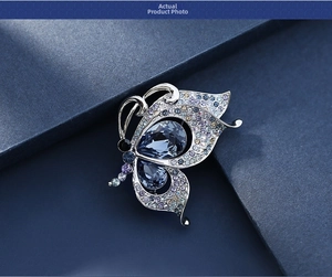 Macro detail of silver butterfly brooch with blue teardrop crystals and mixed rhinestones