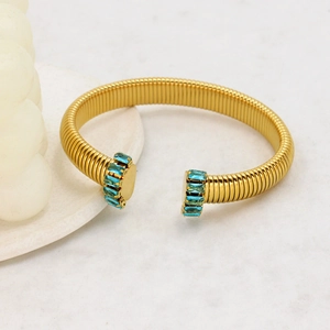 Dettaglio del bracciale aperto dorato a forma di C con zirconi blu chiaro taglio baguette
