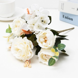 Elegant white artificial rose bouquet with green leaves on a clean white desk setup