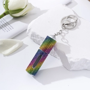 Detail of rainbow rhinestone perfume bottle keychain on white stone with white roses