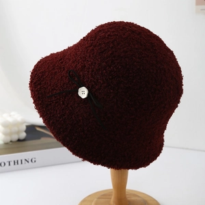 Detailed view of a wine red sherpa bucket hat featuring a black bow and button