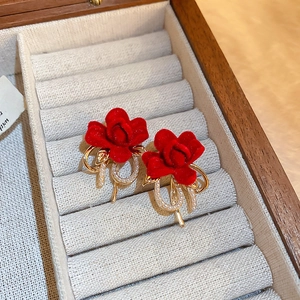 Vue détaillée des boucles d'oreilles rose en velours rouge avec feuilles dorées et perles
