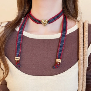 Detail of a woven heart choker featuring golden metal pendant and bohemian beads