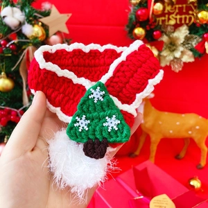 Close-up of red knitted pet Christmas scarf with green tree charm and soft festive decor