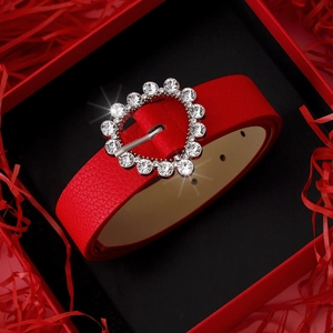 Red leather heart buckle belt with rhinestones in a gift box with red paper shreds