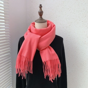 Close-up of soft coral pink cashmere feel scarf featuring classic fringe details on a mannequin