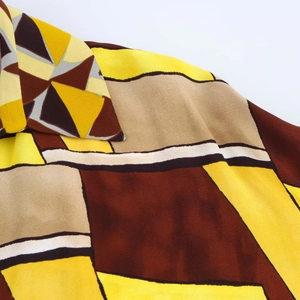 Dettaglio macro del colletto a punta e della stampa geometrica sulla camicia gialla