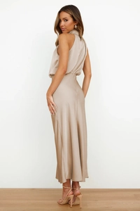 Elegant champagne satin dress featuring a backless halter neck and fluid ankle-length drape