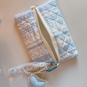 Detail of blue floral quilted pouch with pearl handle, lace ribbon and heart charm