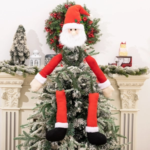 Detailed view of Santa tree topper with plush red hat and long legs on a snowy tree