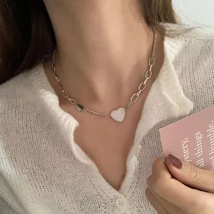 Close-up of asymmetric heart pendant necklace with mixed chain styles on model