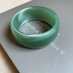 Detailed view of wide bean green acrylic bangle with natural marbled texture