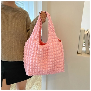 Detail of pink ruffled bubble cloud tote bag held by model in stylish room setting