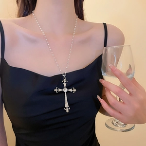 Dettaglio di una collana a croce vintage in argento con cristalli indossata da una modella