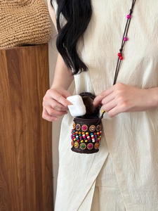 Detail showing Bohemian handmade woven bag holding wireless earbuds in scenario