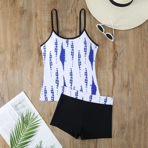 Flat lay of blue tie-dye tankini set with high-waisted boy shorts on wooden floor