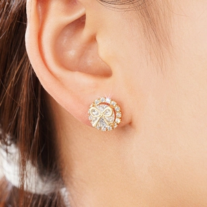 Elegant gold bow stud earrings with cubic zirconia stones shown on the ear