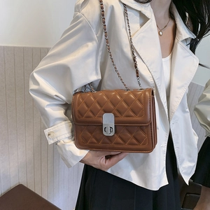 Detail of brown quilted shoulder bag featuring silver chain strap and metal twist-lock