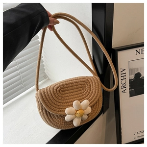 Detail view of khaki woven saddle bag featuring a 3D floral accent and smiley face center