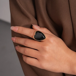 Gros plan de la bague coeur avec pierre noire et finition dorée sur la main