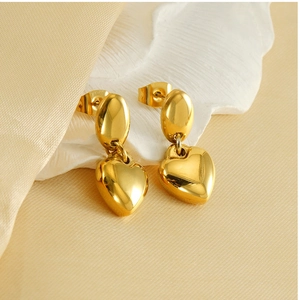 Macro view of polished 18K gold plated heart drop earrings on a soft velvet backdrop