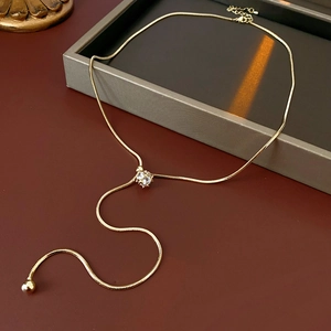 Close-up of gold plated Y-necklace with sphere zircon stone and elegant tassel detail