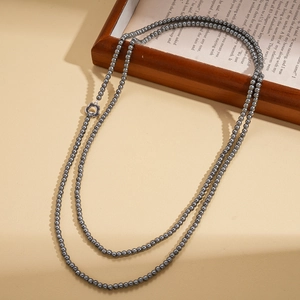 Detail of grey pearl necklace with flower-shaped OT clasp against a vintage background