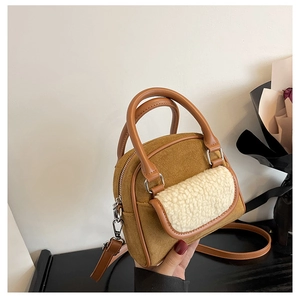 Close-up of brown suede handbag with white faux shearling pocket and leather strap