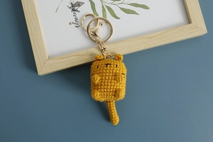 Close-up of yellow crochet cat keychain with golden metal ring and lobster clasp